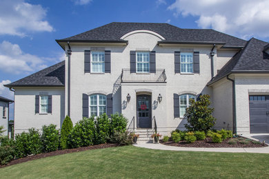 Mid-sized traditional white two-story brick house exterior idea in Other with a hip roof and a shingle roof