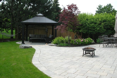 Inspiration for a mid-sized transitional full sun backyard concrete paver landscaping in Toronto with a fire pit for summer.
