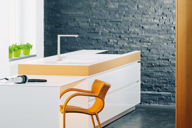 Offene, Zweizeilige Moderne Küche mit integriertem Waschbecken, flächenbündigen Schrankfronten, weißen Schränken, Küchenrückwand in Schwarz, Rückwand aus Steinfliesen, Betonboden und Kücheninsel in Berlin