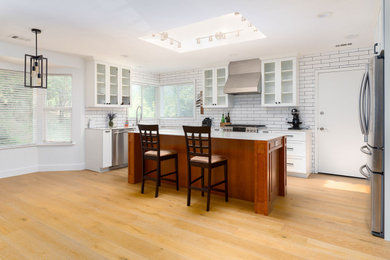Open concept kitchen - huge transitional l-shaped light wood floor open concept kitchen idea in New York with shaker cabinets, white cabinets, quartz countertops, subway tile backsplash, stainless steel appliances and an island