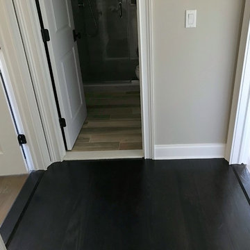 Porcelain wood look floor in bathroom joined by real wood in outer hall and bedr
