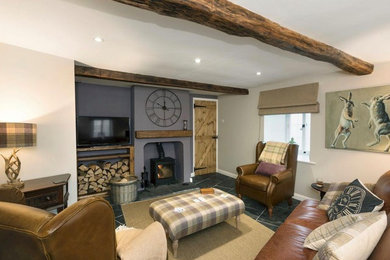 Photo of a medium sized traditional enclosed living room in Other with purple walls, slate flooring, a wood burning stove, a wooden fireplace surround, a freestanding tv and black floors.