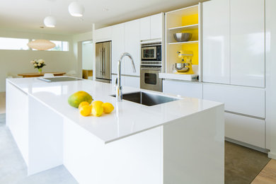 Open concept kitchen - mid-sized modern single-wall concrete floor and gray floor open concept kitchen idea in Seattle with an undermount sink, flat-panel cabinets, white cabinets, quartz countertops, stainless steel appliances, an island and white countertops