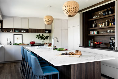 Large trendy u-shaped laminate floor and brown floor eat-in kitchen photo in Seattle with an undermount sink, flat-panel cabinets, quartz countertops, an island, white countertops, white cabinets and paneled appliances