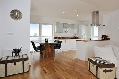 This is an example of a large contemporary open plan dining in Kent with white walls and light hardwood floors.