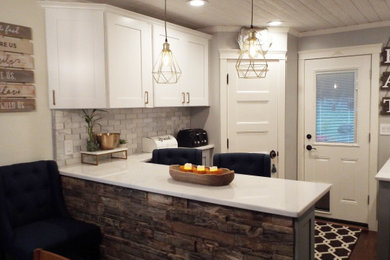 Example of a mid-sized mountain style u-shaped dark wood floor, brown floor and shiplap ceiling enclosed kitchen design in New York with a farmhouse sink, shaker cabinets, quartz countertops, white backsplash, marble backsplash, stainless steel appliances, a peninsula and white countertops