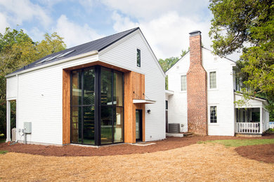 This is an example of a mid-sized modern two-storey white house exterior in Atlanta with a gable roof and a metal roof.