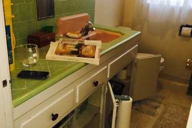Inredning av ett 50 tals mellanstort en-suite badrum, med ett nedsänkt handfat, skåp i shakerstil, vita skåp, kaklad bänkskiva, ett platsbyggt badkar, en dusch/badkar-kombination, en toalettstol med separat cisternkåpa, grön kakel, keramikplattor, beige väggar och klinkergolv i keramik
