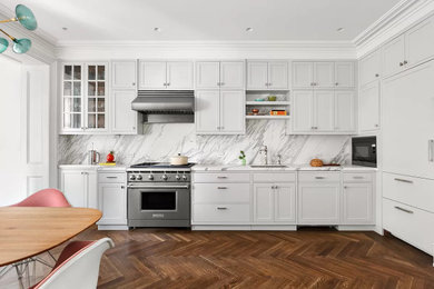 ニューヨークにある高級な中くらいなミッドセンチュリースタイルのおしゃれなキッチン (シングルシンク、シェーカースタイル扉のキャビネット、グレーのキャビネット、大理石カウンター、白いキッチンパネル、大理石のキッチンパネル、パネルと同色の調理設備、無垢フローリング、アイランドなし、茶色い床、白いキッチンカウンター) の写真