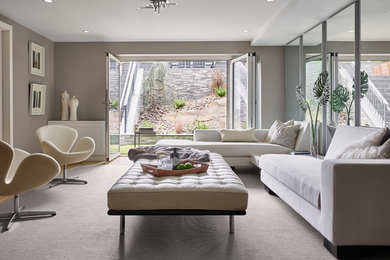 Inspiration for a large modern open concept light wood floor and brown floor family room remodel in New York with gray walls and no fireplace