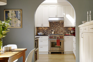 Enclosed kitchen - mid-sized traditional l-shaped light wood floor enclosed kitchen idea in San Francisco with an undermount sink, shaker cabinets, white cabinets, granite countertops, multicolored backsplash, glass tile backsplash, stainless steel appliances and no island