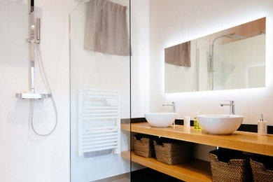 This is an example of a mid-sized scandinavian 3/4 bathroom in Toulouse with a curbless shower, a two-piece toilet, white tile, black tile, cement tile, white walls, a vessel sink, wood benchtops, an open shower and brown benchtops.