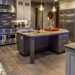 Inspiration för stora rustika kök, med en undermonterad diskho, luckor med infälld panel, skåp i slitet trä, granitbänkskiva, flerfärgad stänkskydd, stänkskydd i glaskakel, rostfria vitvaror, mellanmörkt trägolv och flera köksöar