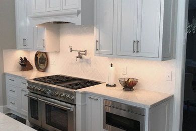 Example of a classic dark wood floor kitchen design in Raleigh with a farmhouse sink, beaded inset cabinets, white cabinets, quartz countertops, white backsplash, ceramic backsplash, stainless steel appliances, an island and white countertops