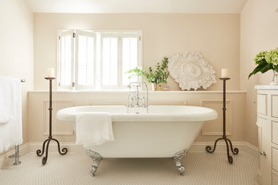 Inspiration for a mid-sized traditional bathroom in Hertfordshire with beige cabinets, a claw-foot tub, a one-piece toilet, beige walls, ceramic floors, marble benchtops, white floor, white benchtops and beaded inset cabinets.