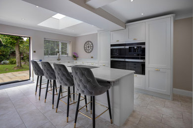 Design ideas for a large modern kitchen in Other with an integrated sink, shaker cabinets, white cabinets, quartz worktops, white splashback, black appliances, porcelain flooring, an island, white worktops and exposed beams.
