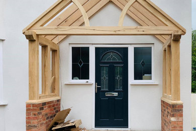 This is an example of a large front door in West Midlands with white walls, brick flooring, a single front door, exposed beams and brick walls.