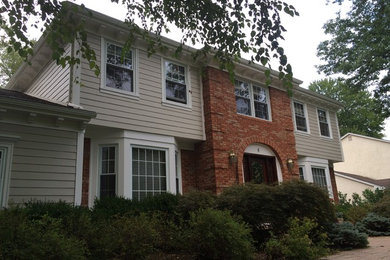 Large elegant beige two-story concrete fiberboard exterior home photo in New York with a hip roof