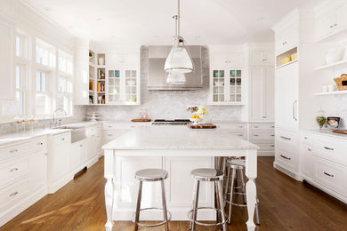 Elegant u-shaped medium tone wood floor and brown floor kitchen photo in Calgary with shaker cabinets, white cabinets, white backsplash, subway tile backsplash, white appliances and an island