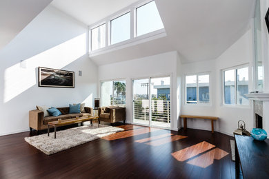 Inspiration for a mid-sized coastal loft-style medium tone wood floor living room remodel in Los Angeles with white walls, a standard fireplace, a stone fireplace and a wall-mounted tv