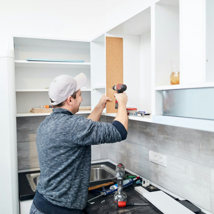 A man fixing a kitchen cabinet