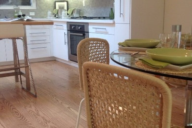 Example of a l-shaped medium tone wood floor kitchen design in San Francisco with flat-panel cabinets, white cabinets, gray backsplash and stone tile backsplash