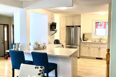 Inspiration for a mid-sized transitional l-shaped vinyl floor and beige floor open concept kitchen remodel in Other with a drop-in sink, shaker cabinets, beige cabinets, laminate countertops, gray backsplash, ceramic backsplash, stainless steel appliances, an island and multicolored countertops