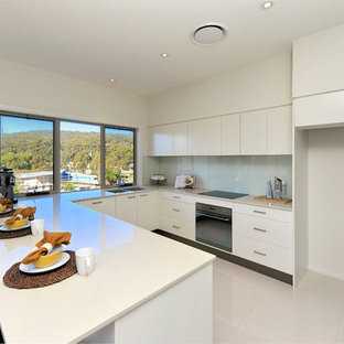 Mid-sized modern kitchen pantry pictures - Example of a mid-sized minimalist u-shaped porcelain floor kitchen pantry design in Newcastle - Maitland with an undermount sink, white cabinets, quartz countertops, white backsplash, glass sheet backsplash, stainless steel appliances and no island
