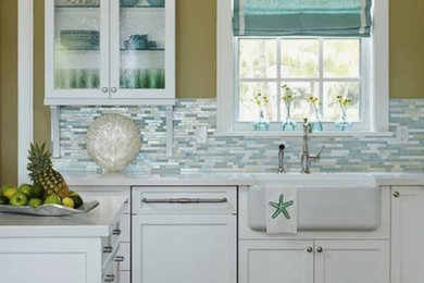 Inredning av ett vit vitt kök, med luckor med glaspanel, vita skåp, flerfärgad stänkskydd och stänkskydd i glaskakel