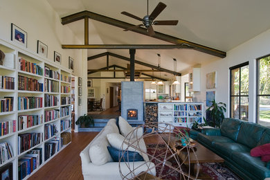 Large country open concept living room in San Francisco with a library, white walls, medium hardwood floors, a two-sided fireplace, a tile fireplace surround, brown floor and no tv.