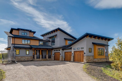 Inspiration for a transitional gray two-story stucco house exterior remodel in Calgary with a shed roof and a shingle roof