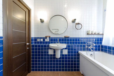 Mid-sized contemporary bathroom in Moscow with a freestanding tub, a wall-mount toilet, multi-coloured tile, ceramic tile, white walls, ceramic floors, a wall-mount sink and brown floor.