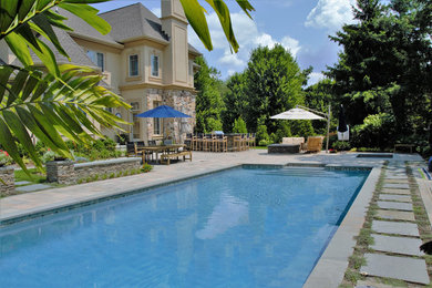 Inspiration for a large contemporary backyard stone and rectangular hot tub remodel in New York