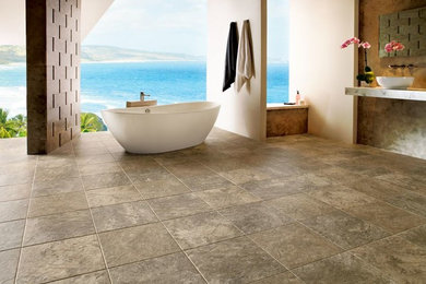 Inspiration for a large tropical master bathroom in St Louis with limestone floors, a freestanding tub, beige tile, cement tile, beige walls, a vessel sink and solid surface benchtops.