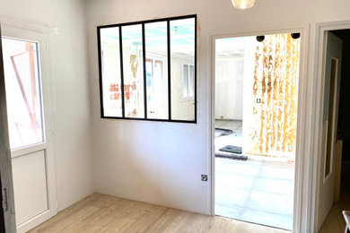 他の地域にあるお手頃価格の中くらいなインダストリアルスタイルのおしゃれな玄関ロビー (白い壁、ラミネートの床、白いドア、茶色い床) の写真