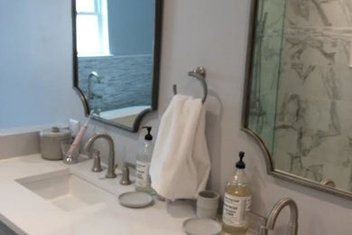 Bathroom - mid-sized transitional master marble tile porcelain tile and gray floor bathroom idea in New Orleans with recessed-panel cabinets, gray cabinets, gray walls, an undermount sink, solid surface countertops, a hinged shower door and white countertops