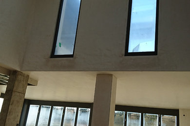 ドルトムントにあるラグジュアリーな巨大なコンテンポラリースタイルのおしゃれなリビング (白い壁、コンクリートの床、標準型暖炉、漆喰の暖炉まわり、壁掛け型テレビ) の写真