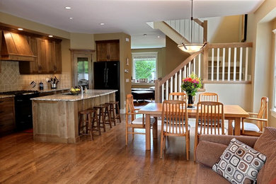 Mid-sized elegant u-shaped medium tone wood floor kitchen photo in Calgary with an undermount sink, shaker cabinets, medium tone wood cabinets, granite countertops, beige backsplash, porcelain backsplash, black appliances and an island