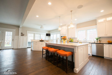 Inspiration for a huge timeless l-shaped medium tone wood floor and brown floor eat-in kitchen remodel in Other with a farmhouse sink, raised-panel cabinets, white cabinets, granite countertops, white backsplash, subway tile backsplash, stainless steel appliances and two islands