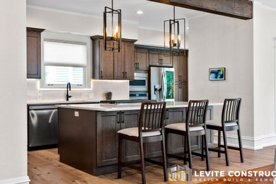 Example of a single-wall light wood floor eat-in kitchen design in Seattle with a drop-in sink, raised-panel cabinets, dark wood cabinets, marble countertops, white backsplash, marble backsplash, stainless steel appliances, an island and white countertops
