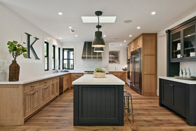 Kitchen - transitional u-shaped medium tone wood floor kitchen idea in San Francisco with shaker cabinets, medium tone wood cabinets, white backsplash, stainless steel appliances, an island and white countertops