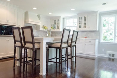 Eat-in kitchen - mid-sized transitional l-shaped dark wood floor and brown floor eat-in kitchen idea in New York with recessed-panel cabinets, white cabinets, marble countertops, gray backsplash, stone tile backsplash, stainless steel appliances and an island