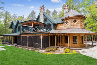 Diseño de fachada de casa verde de estilo americano de dos plantas con revestimiento de madera, tejado a dos aguas, tejado de teja de madera y tablilla