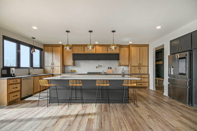 Inspiration for a large modern l-shaped laminate floor and beige floor open concept kitchen remodel in Grand Rapids with an undermount sink, light wood cabinets, quartz countertops, white backsplash, ceramic backsplash, stainless steel appliances, an island and white countertops