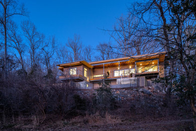 Immagine della villa marrone moderna a due piani di medie dimensioni con rivestimento in stucco, tetto a farfalla, copertura in metallo o lamiera e tetto grigio