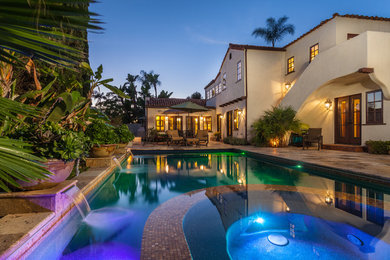 Photo of a large mediterranean backyard rectangular lap pool in San Diego with a hot tub and natural stone pavers.
