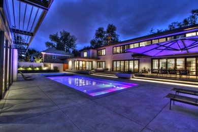 Mid-sized minimalist backyard stamped concrete and rectangular lap hot tub photo in Denver