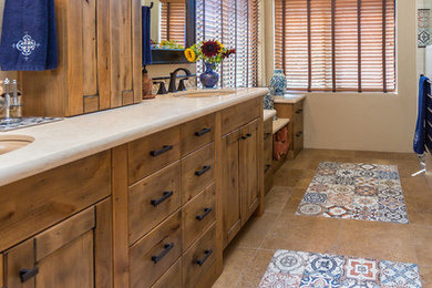 Example of a large southwest 3/4 beige tile travertine floor and brown floor corner shower design in Phoenix with recessed-panel cabinets, medium tone wood cabinets, beige walls, an undermount sink, quartz countertops and a hinged shower door
