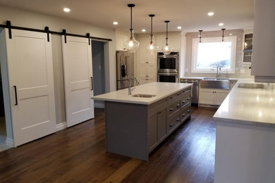 Inspiration for a huge timeless l-shaped light wood floor and beige floor kitchen remodel in Toronto with a farmhouse sink, shaker cabinets, gray cabinets, quartz countertops, white backsplash, ceramic backsplash, stainless steel appliances, an island and white countertops
