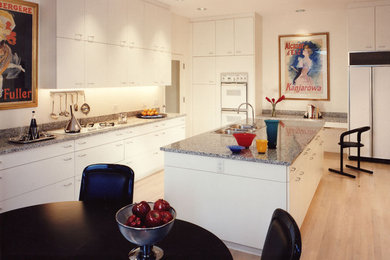 Eat-in kitchen - large contemporary u-shaped light wood floor eat-in kitchen idea in Chicago with a drop-in sink, flat-panel cabinets, white cabinets, granite countertops, white backsplash, stainless steel appliances, an island and gray countertops